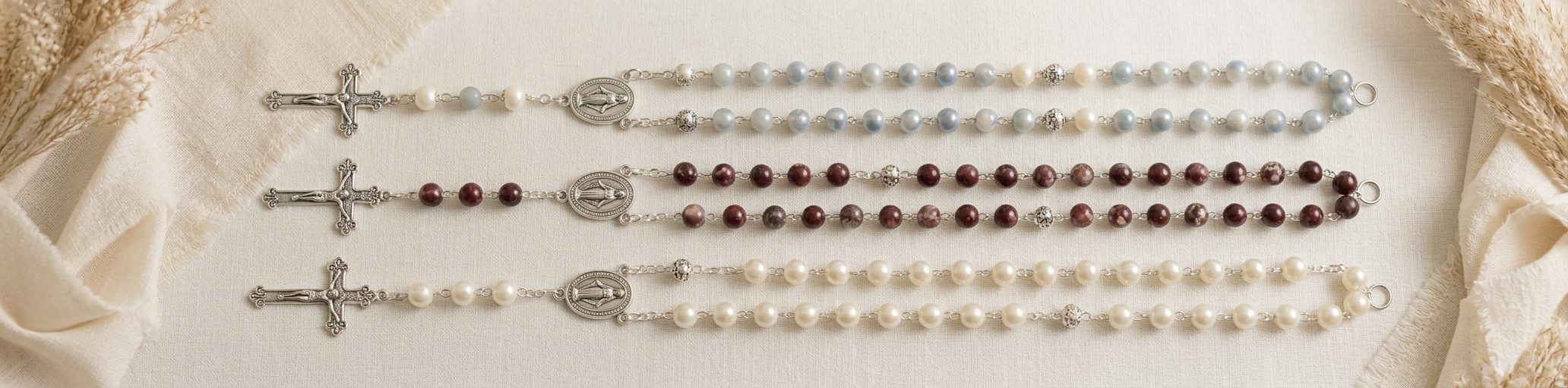 Three handmade rosaries laid out on ivory linen for a custom bundle